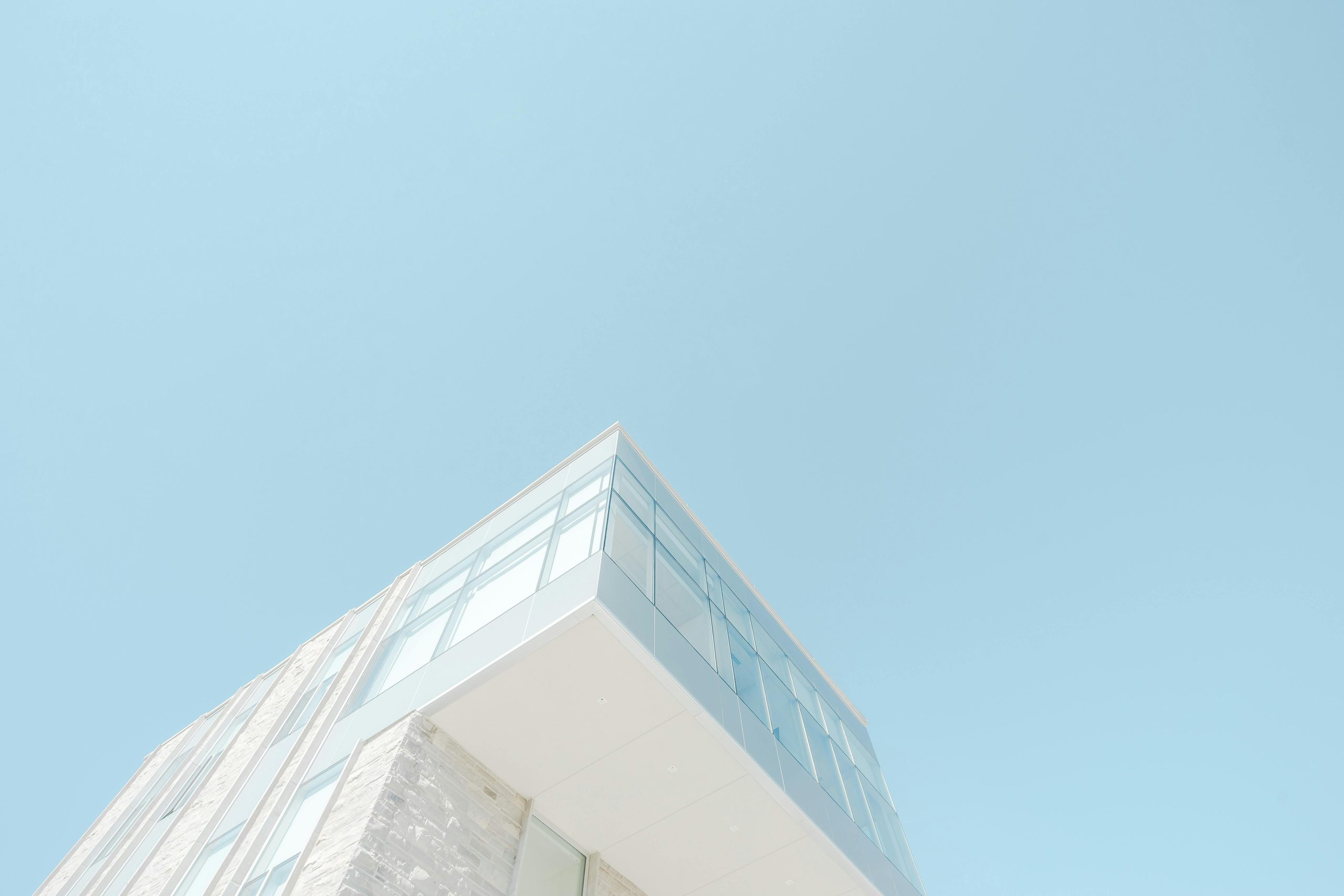 A low-angle shot of a modern building with a glass facade against a bright blue sky in London, Canada.