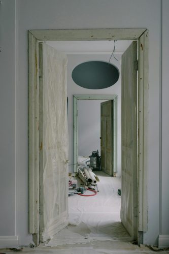 Interior view of an apartment under renovation with open doors and tools.