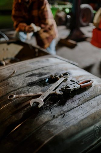 Wrenches and pliers on a greasy workbench in a workshop.